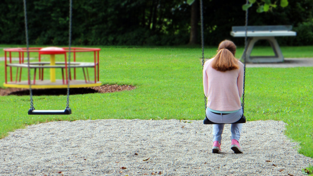 A girl sitting on a swing suffering with mental health problems