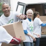 Volunteers passing cardboard boxes from delivery van